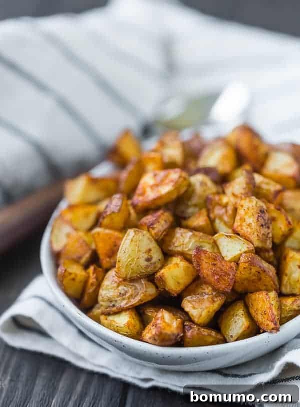 Close up view of small pieces of roasted potatoes in a small oval shaped white bowl.
