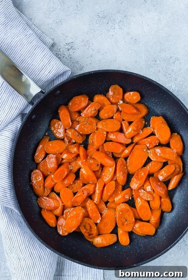 Perfectly caramelized brown sugar and bourbon glazed carrots, shimmering and ready to be served from a black nonstick skillet.