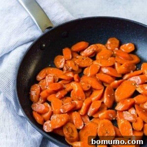 Black non stick skillet with glazed sliced carrots.