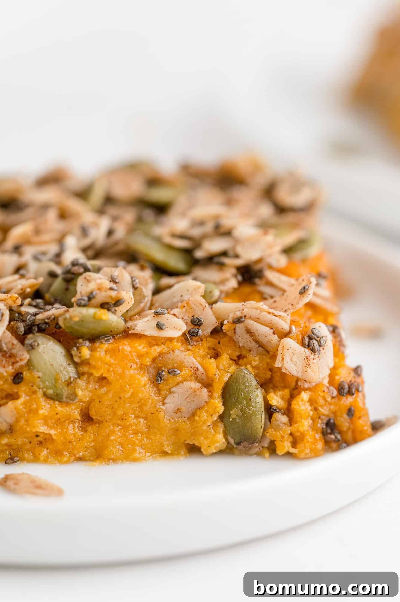 A delectable slice of healthy sweet potato casserole, artfully topped with a crunchy mixture of chia seeds, oats, and pepitas, ready to be enjoyed.