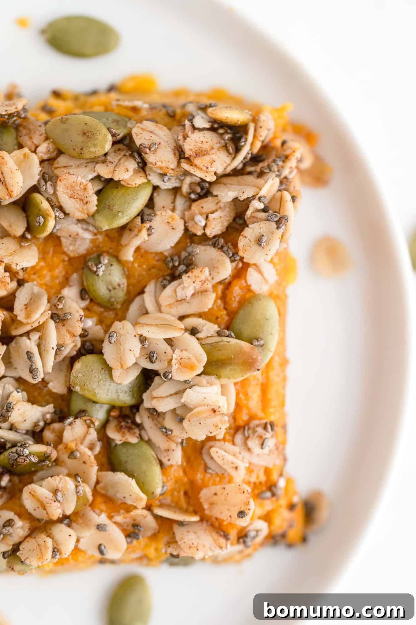 An overhead shot of a perfectly square serving of healthy sweet potato casserole, artfully placed on a round white plate.
