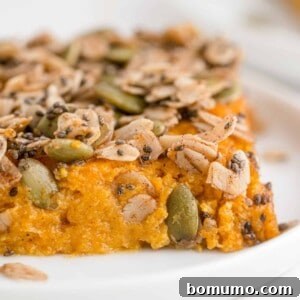 Slice of healthy sweet potato casserole topped with chia seeds, oats, and pepitas.