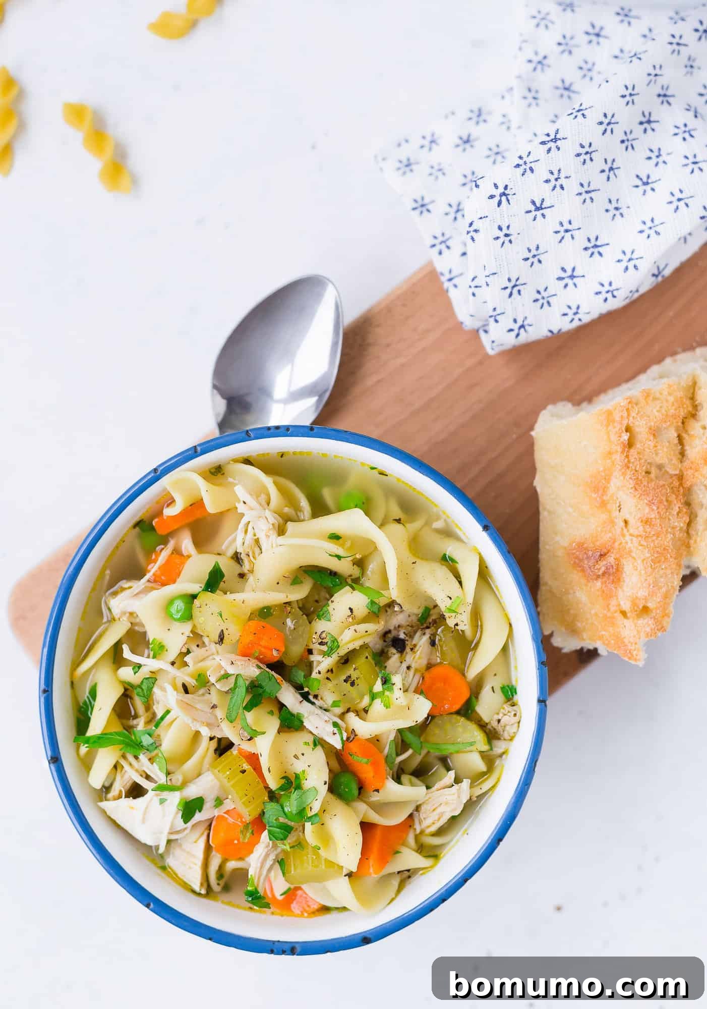 A steaming bowl of Instant Pot Chicken Noodle Soup in a blue and white patterned bowl, garnished with fresh parsley.
