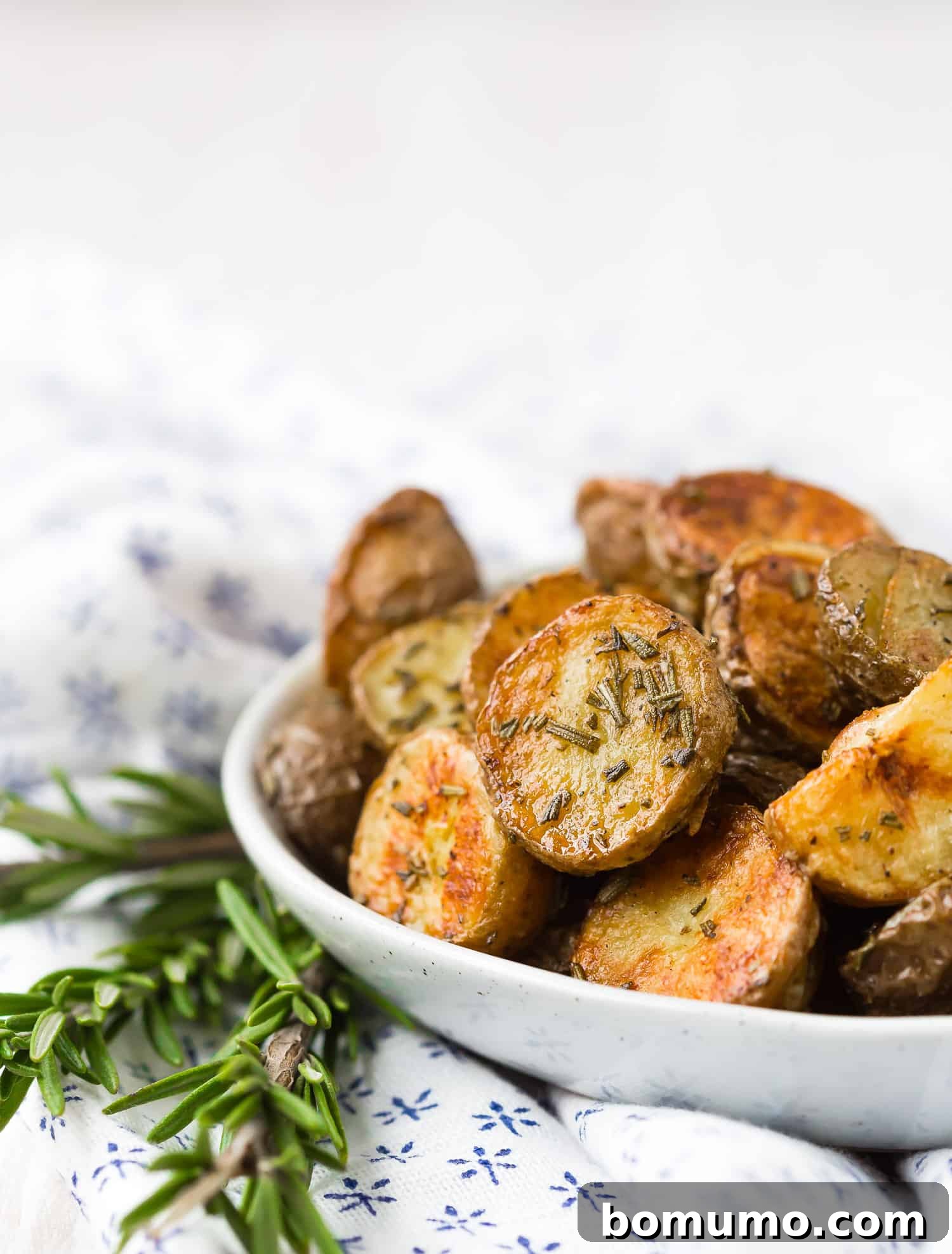 Rosemary roasted potatoes in a small white bowl.