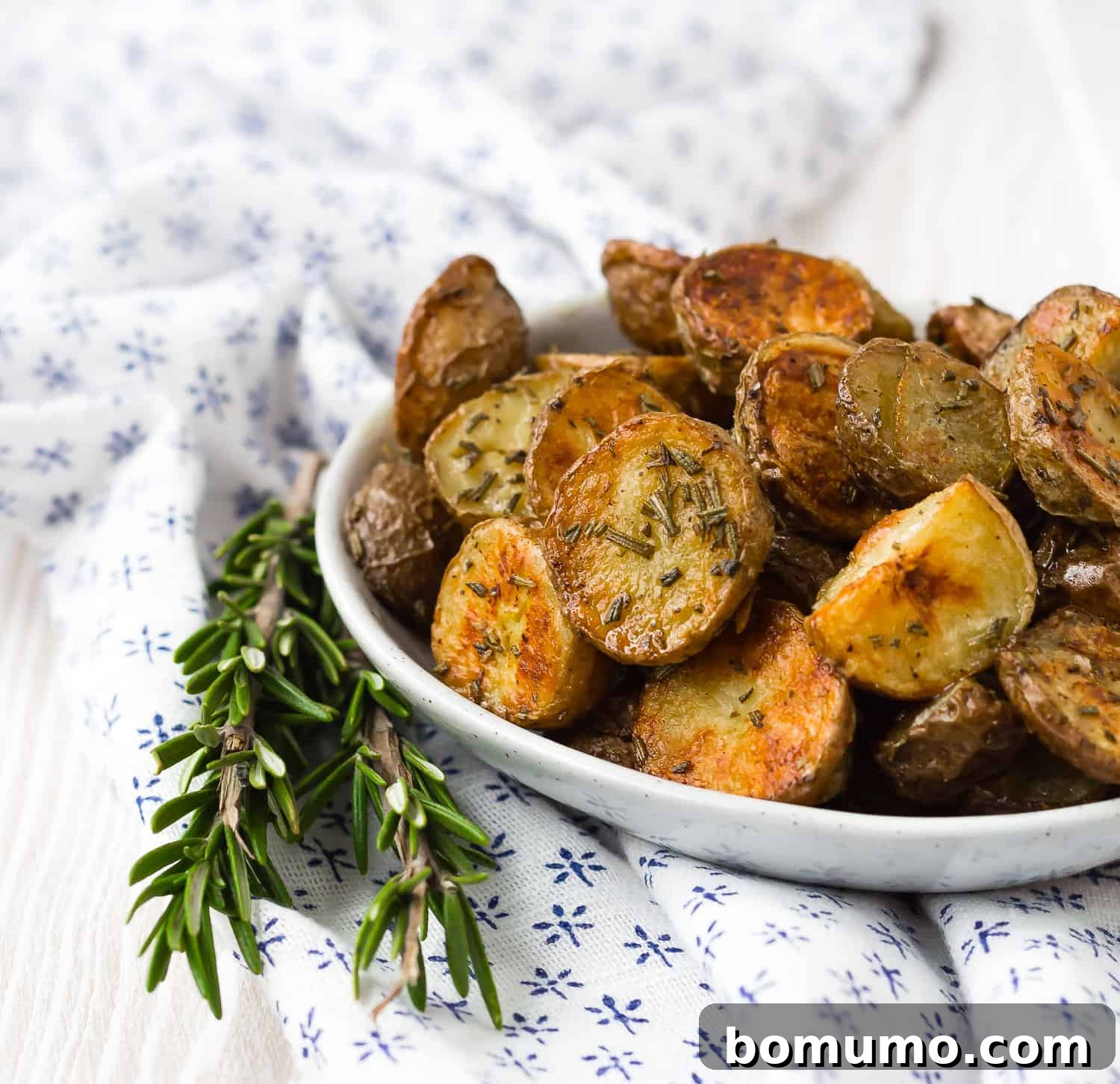 Roasted potatoes with rosemary in small bowl.