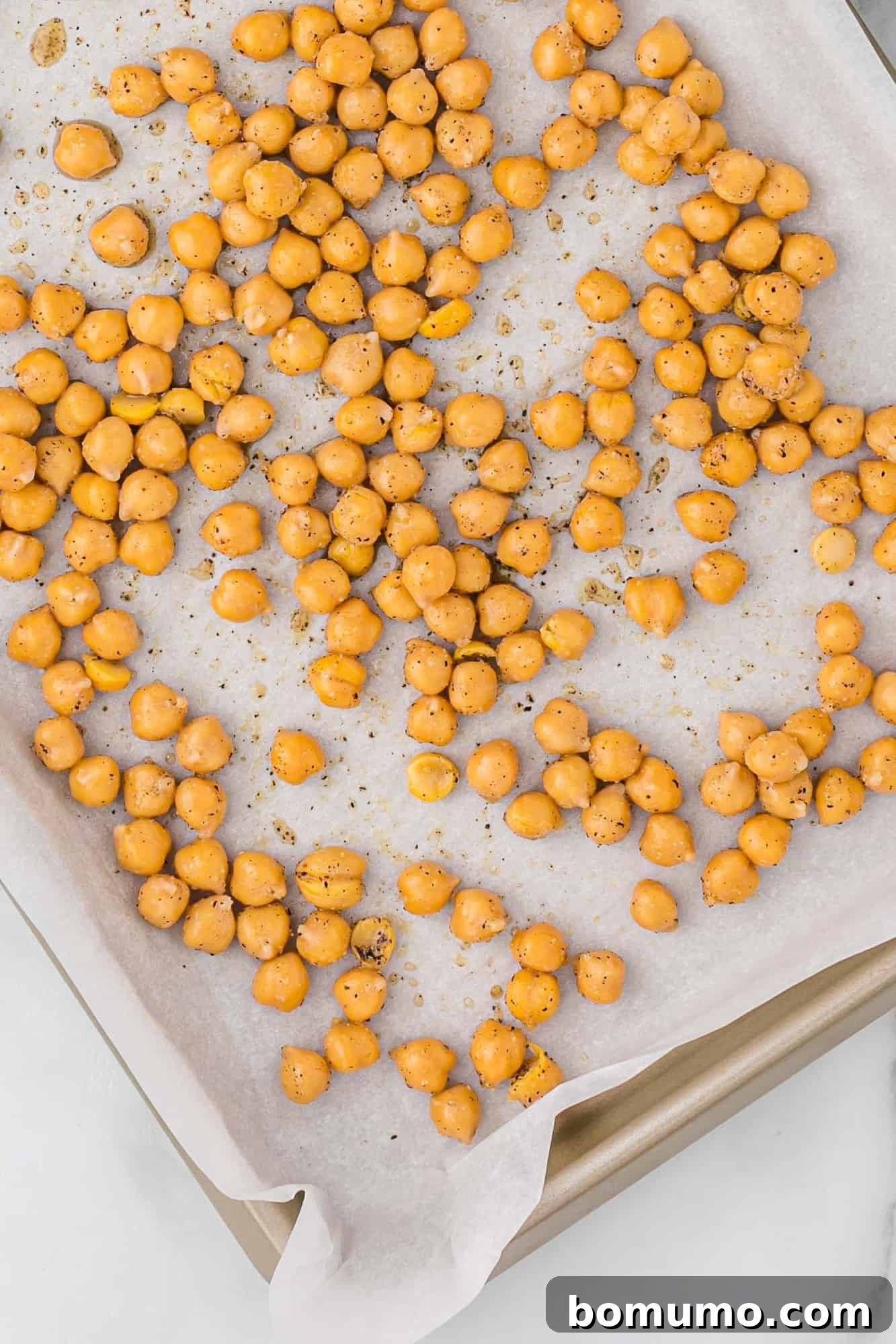 Chickpeas before roasting, seasoned on a sheet pan.