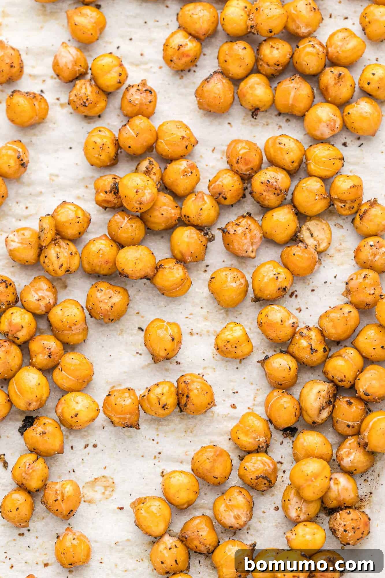 Close up of roasted chickpeas with salt and pepper on a white surface, ready to eat.