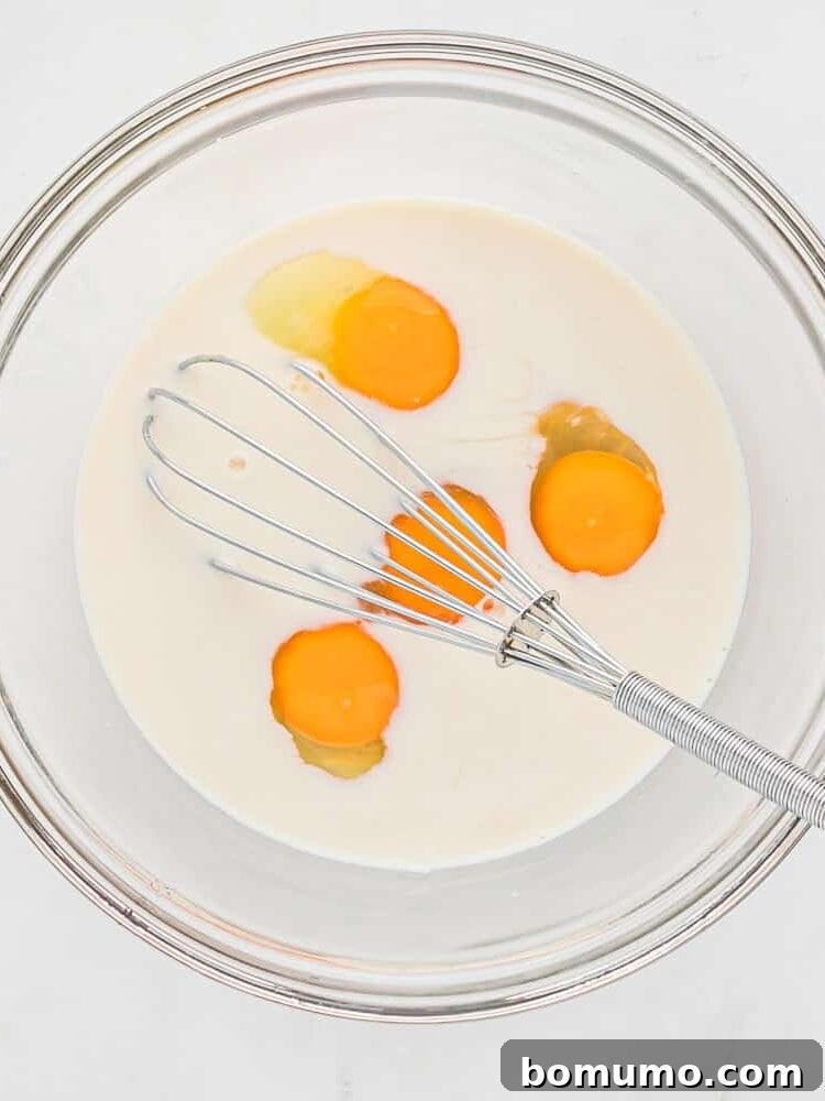 Eggs and milk in a bowl with a whisk.
