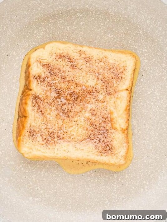 French toast, partially cooked, in a frying pan.