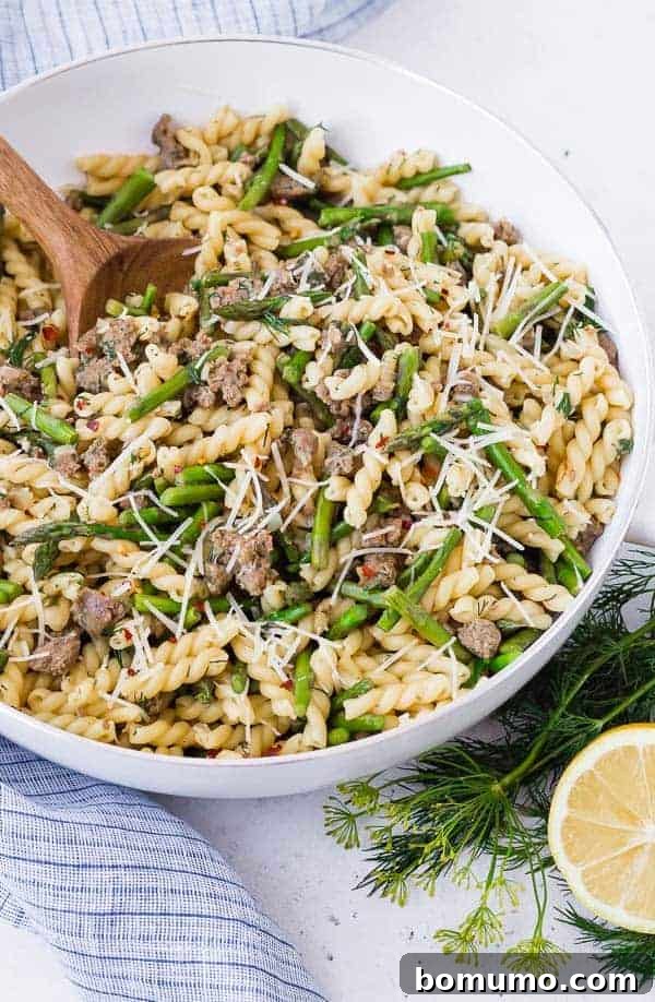 Vibrant One-Pan Lemon Pasta with Sausage and Asparagus, garnished with fresh dill and lemon slices in a white skillet.