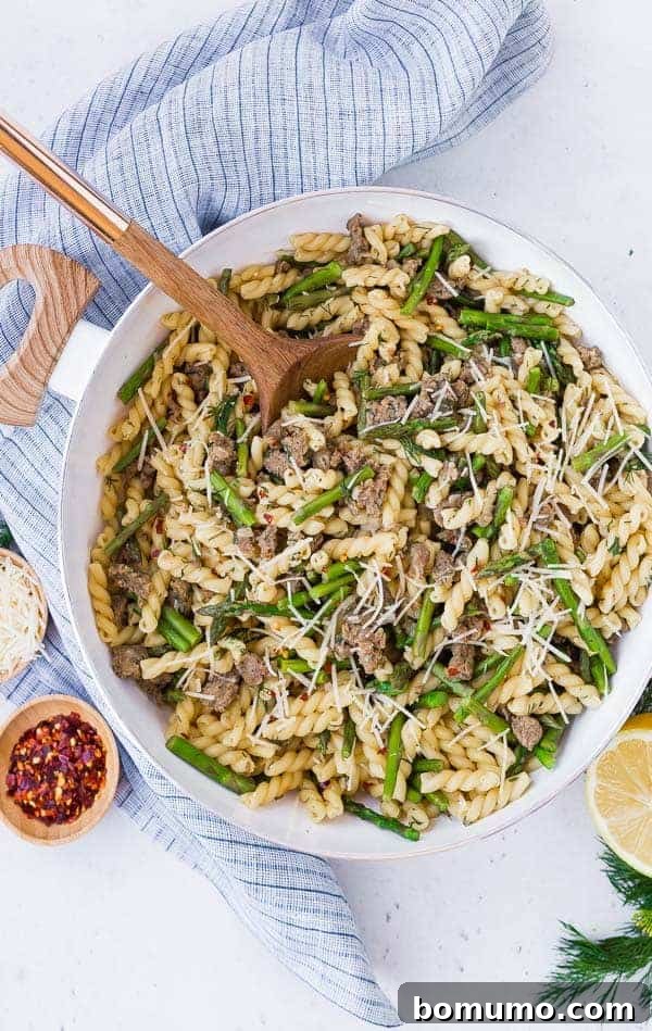 One-Pan Lemon Pasta in a white bowl with a wooden spoon, showcasing the rich texture and vibrant ingredients.