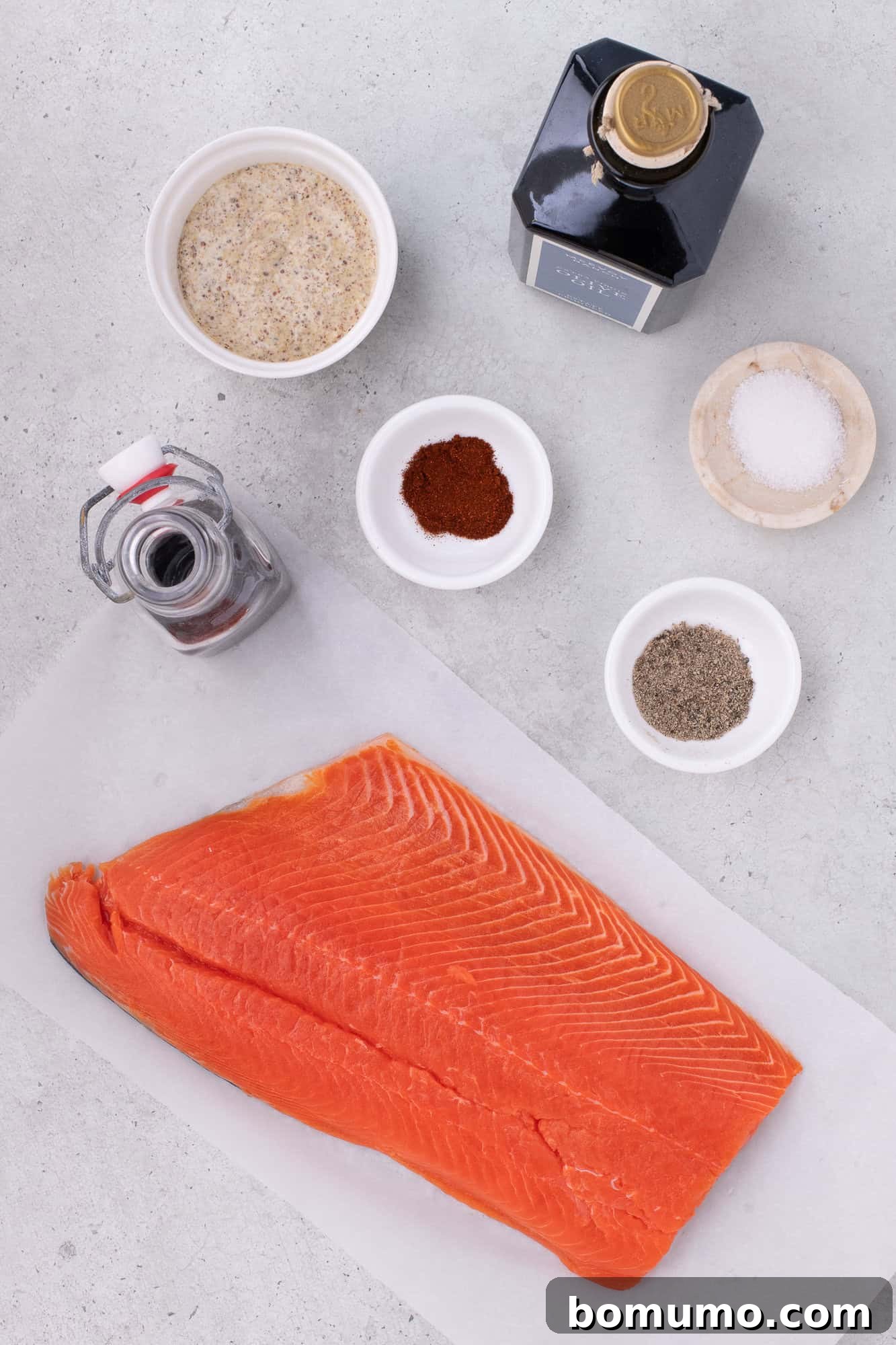 Overhead view of ingredients needed for the maple mustard salmon recipe, including a salmon fillet, Dijon mustard, maple syrup, olive oil, and spices.