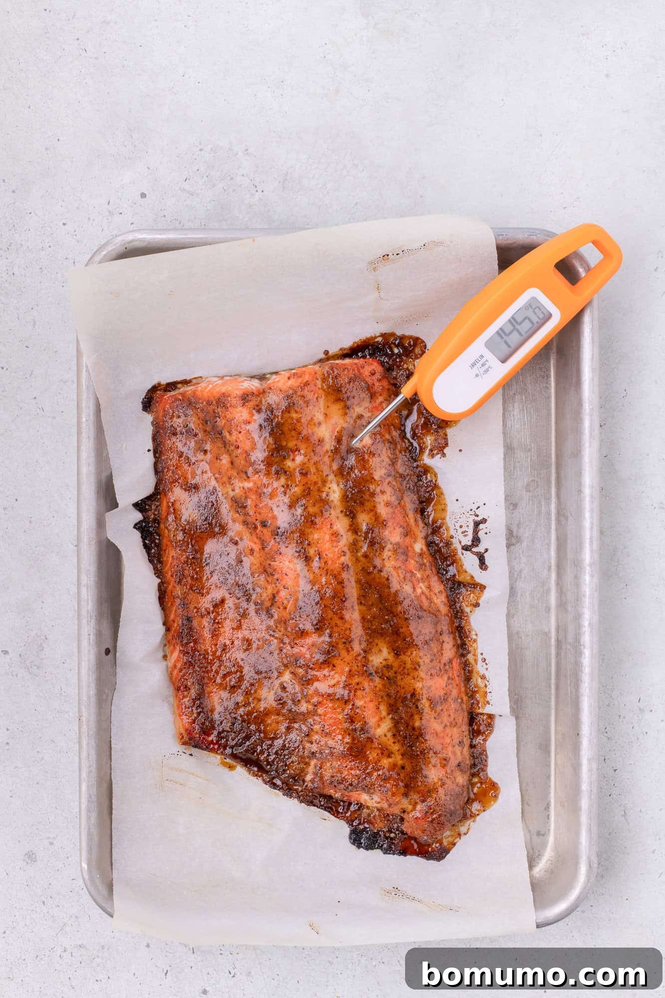 Internal temperature of salmon being checked with an instant-read thermometer, showing it has reached 145 degrees F.
