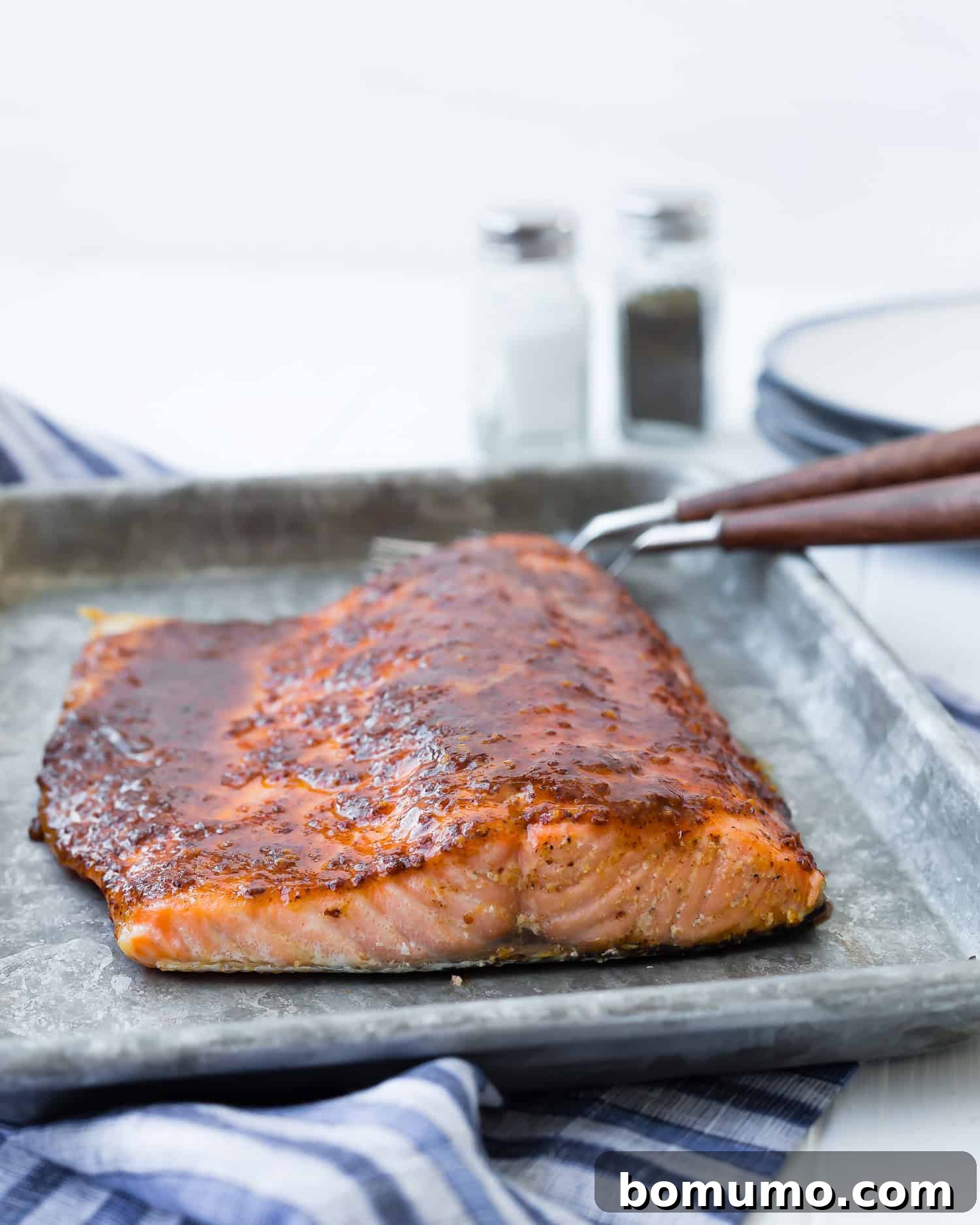 Close-up of perfectly baked maple mustard salmon on a sheet pan, garnished and ready to serve.