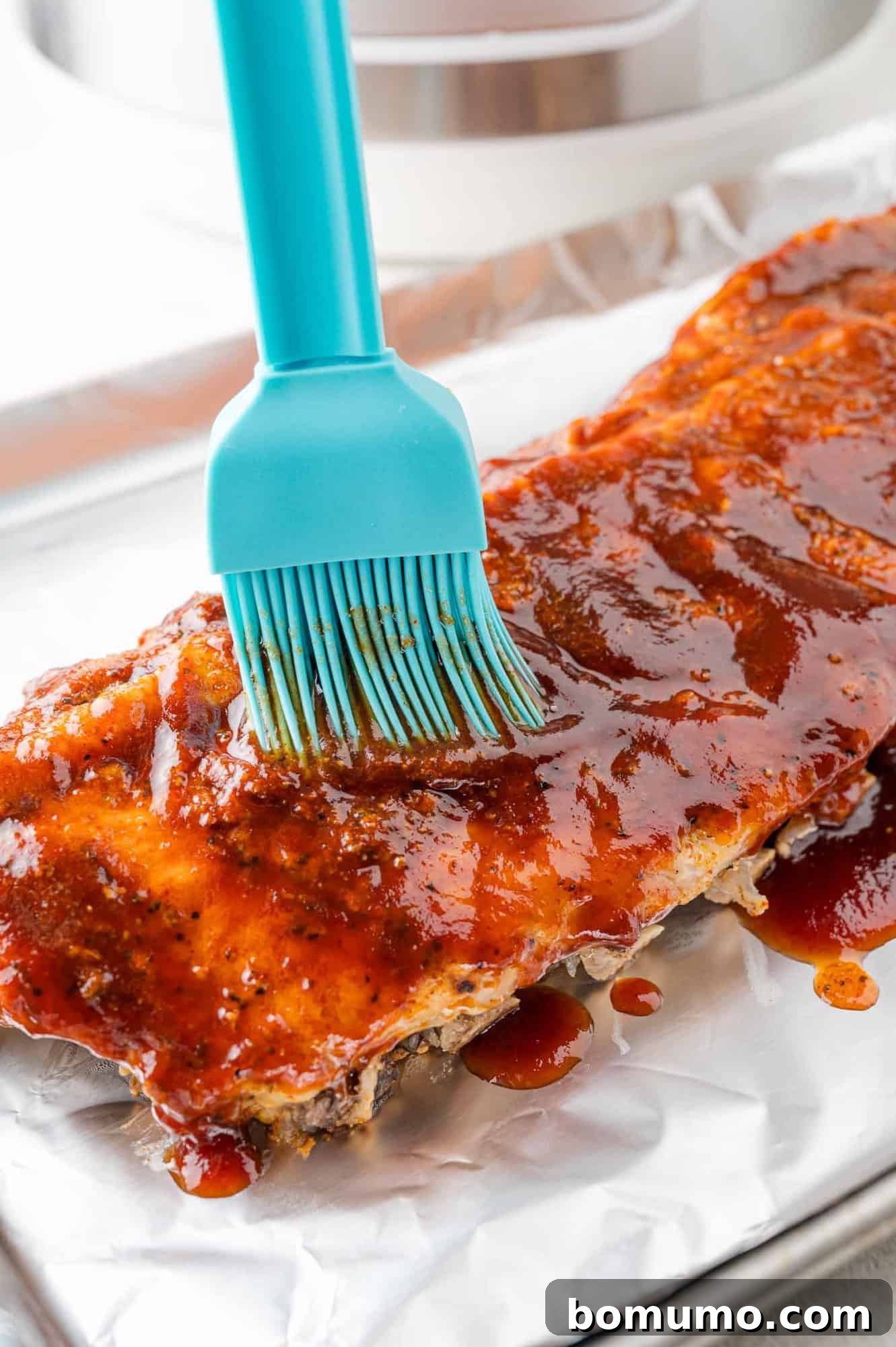 Instant Pot Ribs: Quick & Delicious 10 Cooked ribs being brushed with bbq sauce.