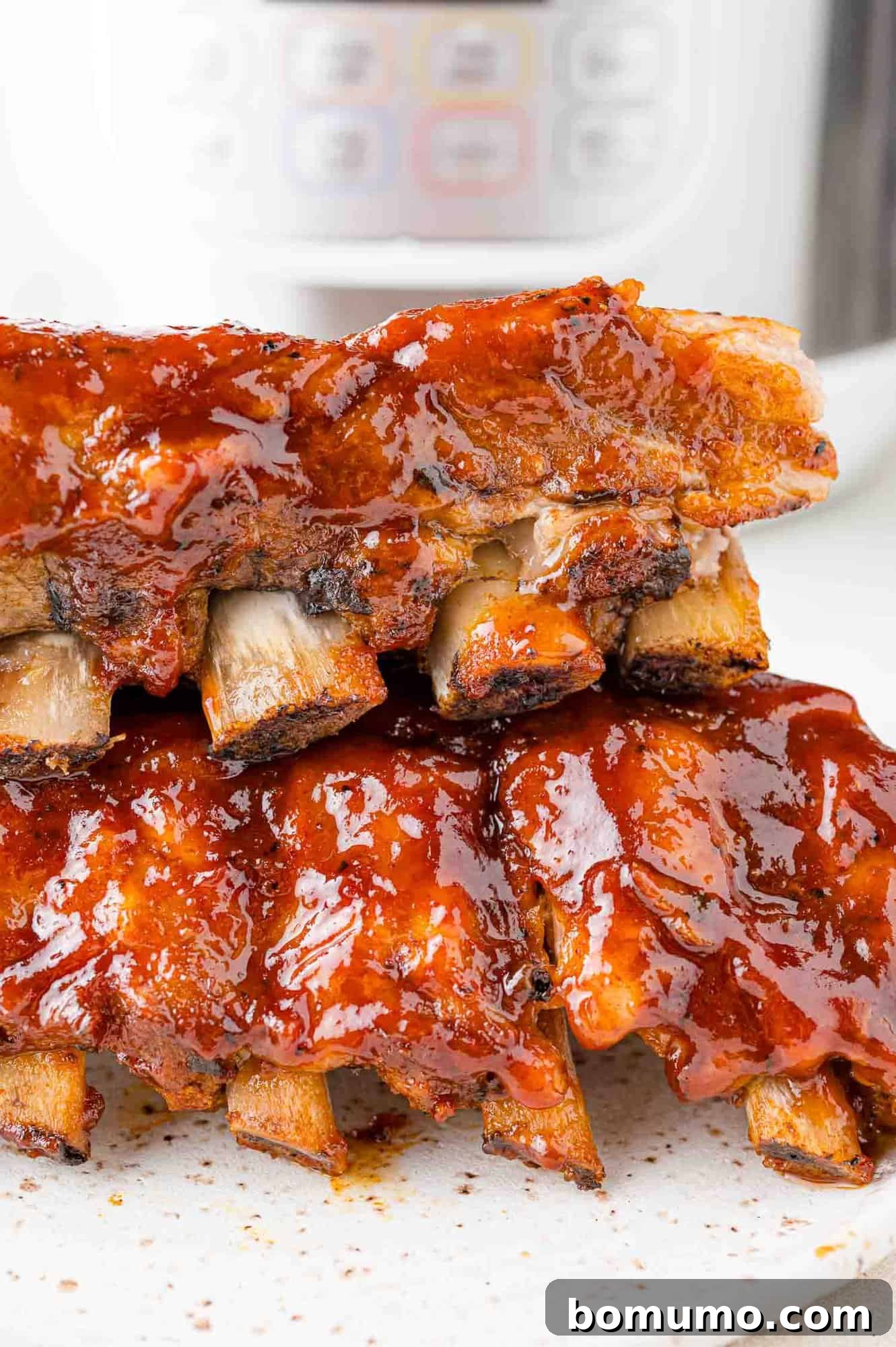 Instant Pot Ribs: Quick & Delicious 2 Instant pot ribs stacked in front of a pressure cooker.