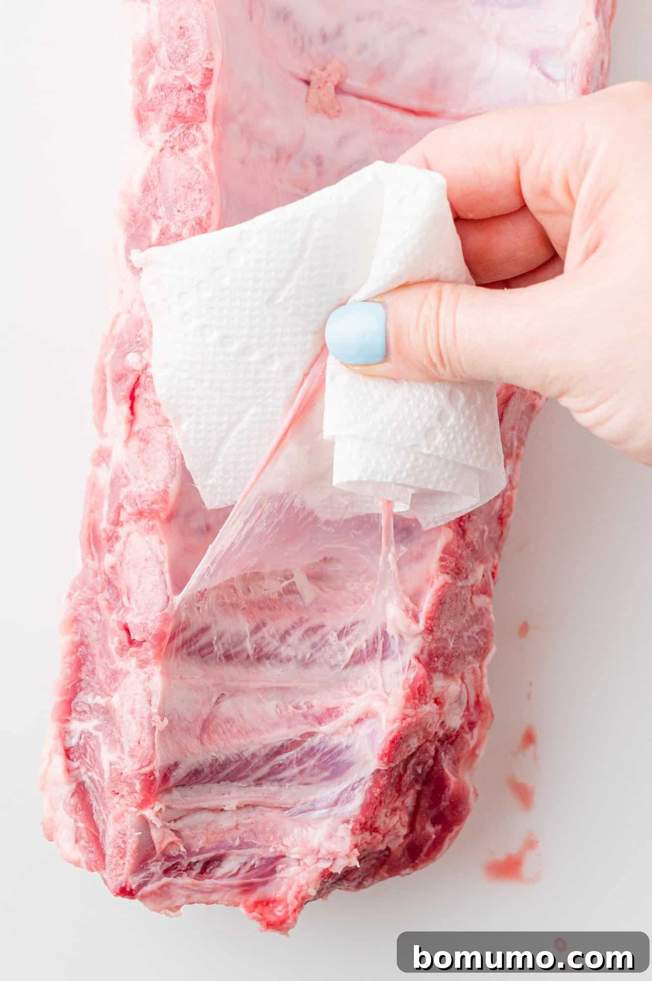 Instant Pot Ribs: Quick & Delicious 7 Membrane being pulled off rack of ribs.