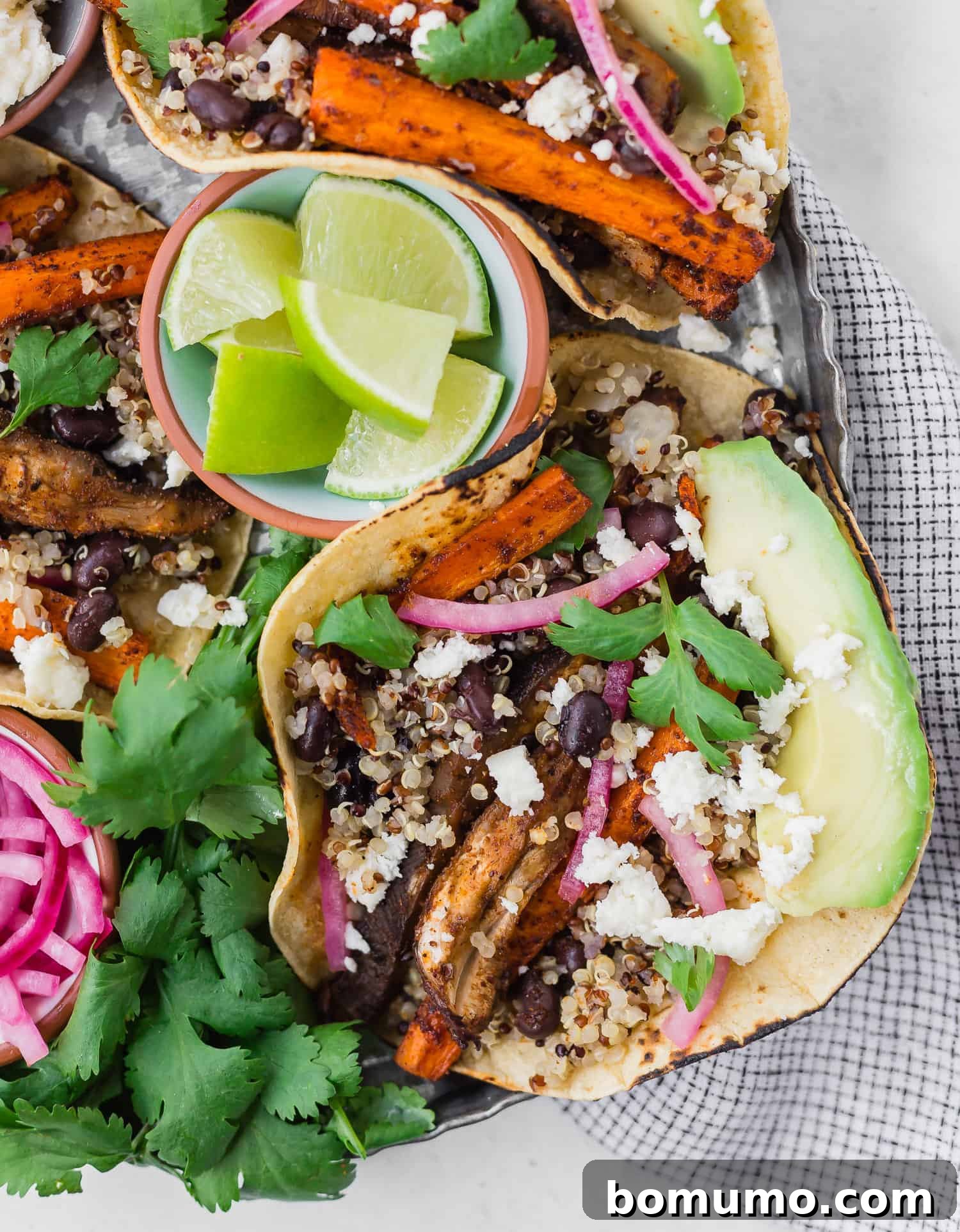 Plant Powered Roasted Tacos 4 A single, perfectly assembled taco rests on a dark tray, adorned with vibrant cilantro, a wedge of lime, and tangy pickled onions.