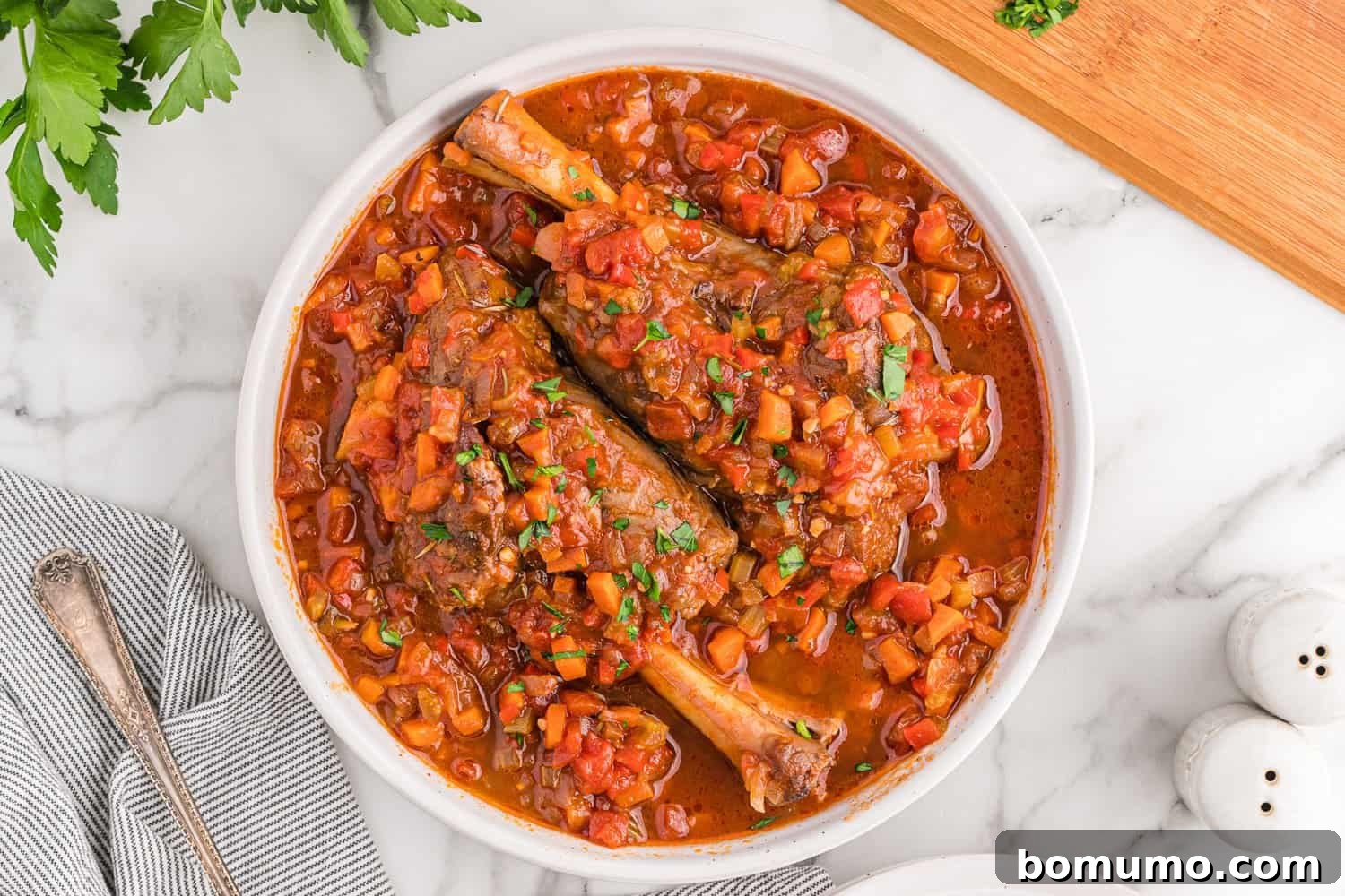 Two perfectly braised lamb shanks, glistening with sauce and adorned with fresh herbs, resting invitingly in a rustic bowl.