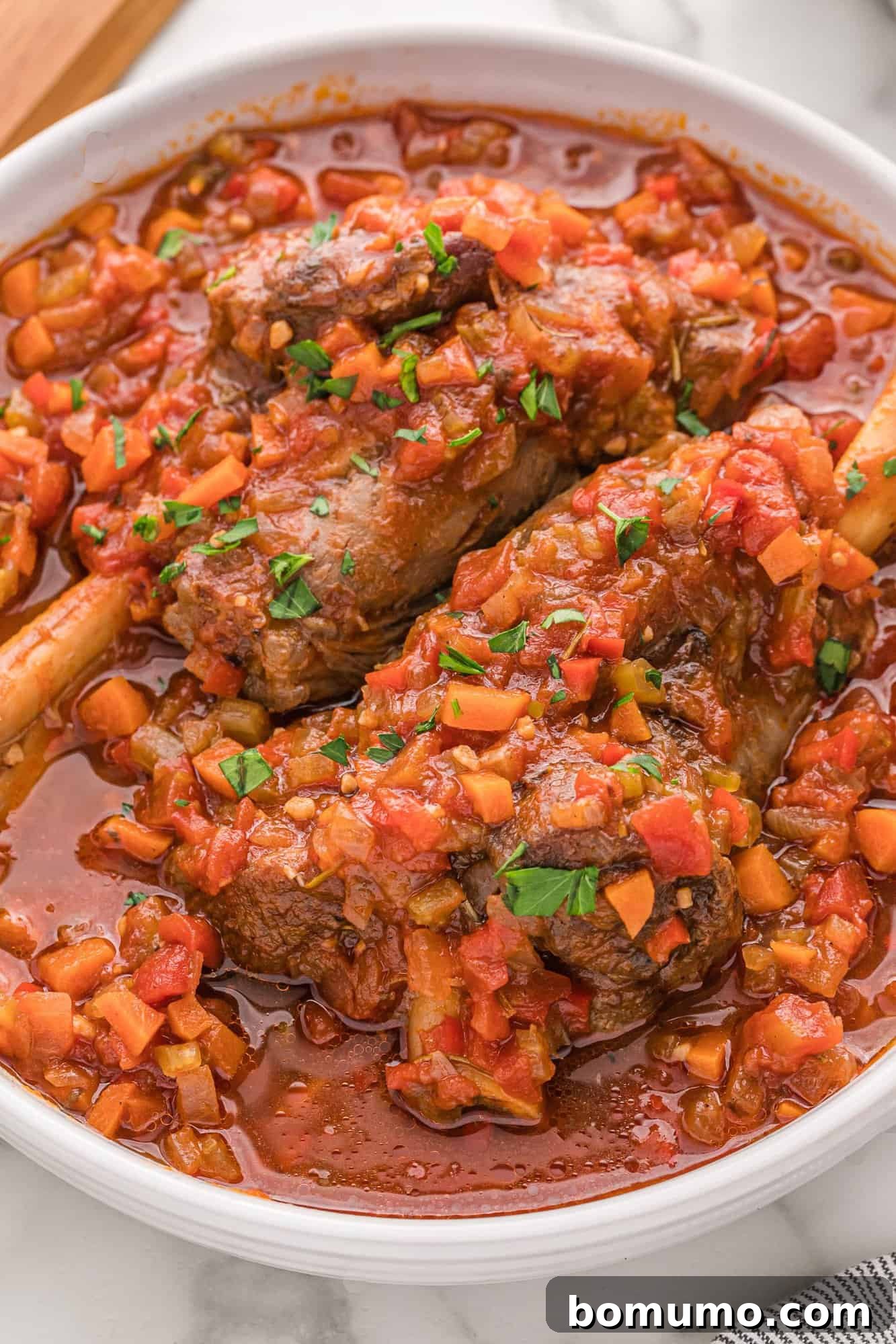 Close-up of lamb shanks immersed in a rich, dark braising liquid, ready for slow cooking to achieve ultimate tenderness.