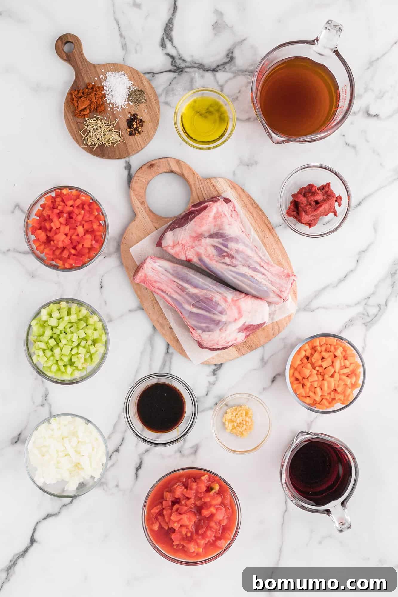 A vibrant selection of ingredients laid out on a countertop, featuring raw lamb shanks, ripe diced tomatoes, fresh carrots, and a bottle of dry red wine, all essential for crafting the perfect braised lamb dish.