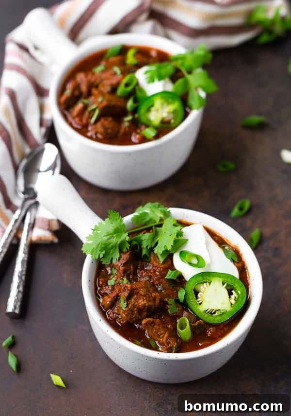 Two bowls of chili, garnished, with spoons and napkins nearby.