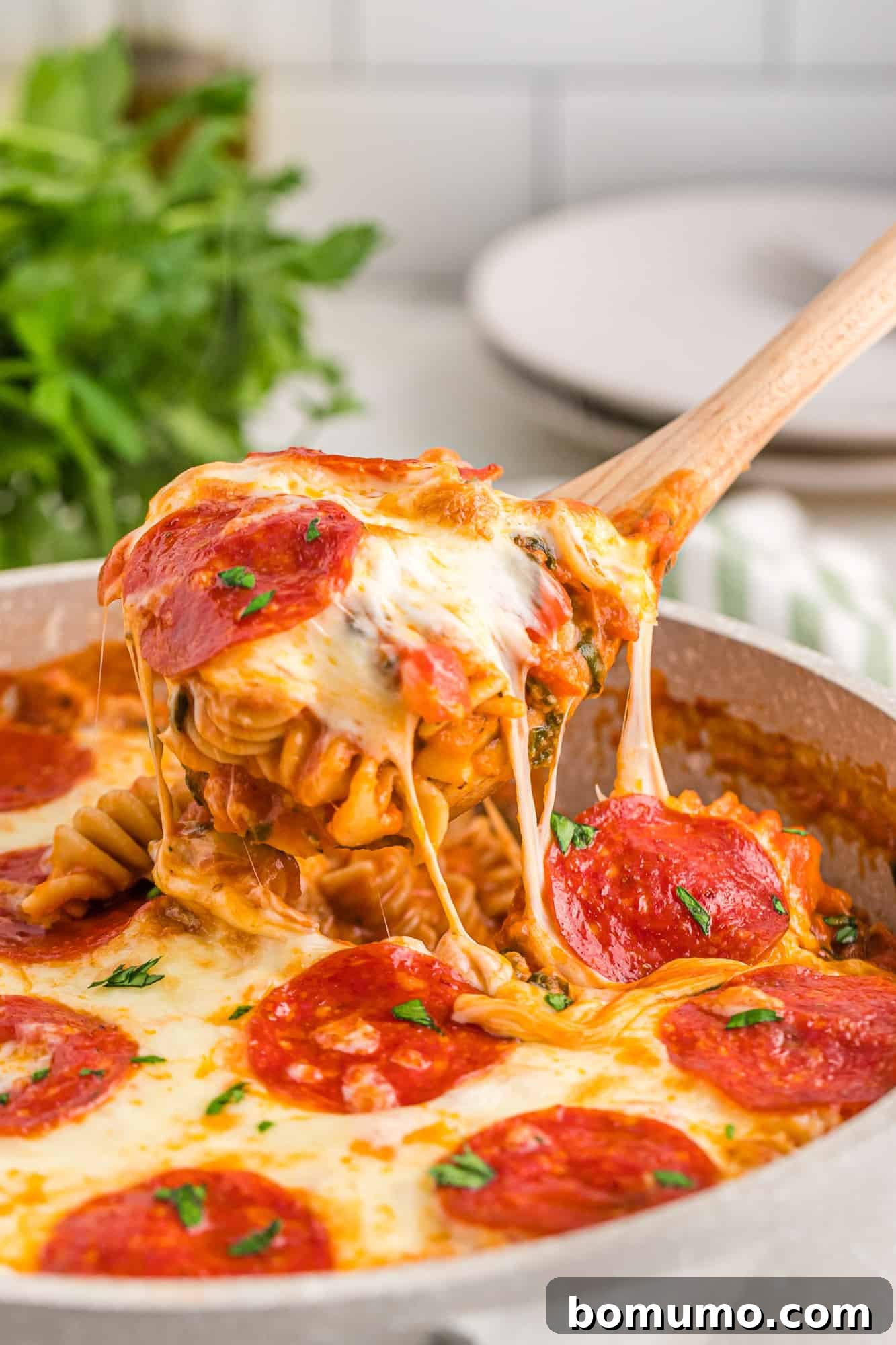 Hearty One-Pan Pizza Pasta being scooped out of a baking dish, showcasing melted cheese and pepperoni.