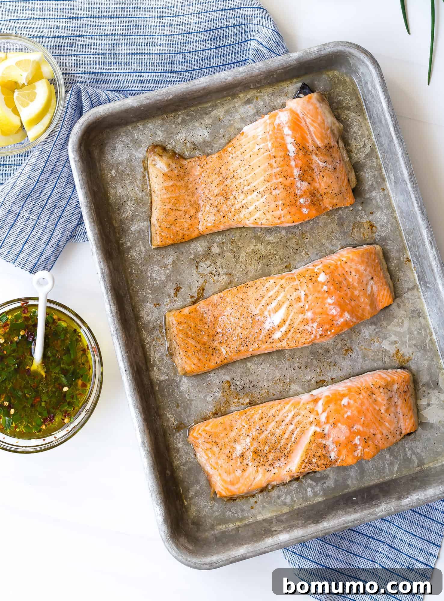 This flavorful baked salmon with lemon and chives is a taste of summer! It's the ultimate healthy, easy dinner idea, ready in 30 minutes. Salmon fillets on a baking sheet, lightly seasoned with kosher salt and freshly ground black pepper.