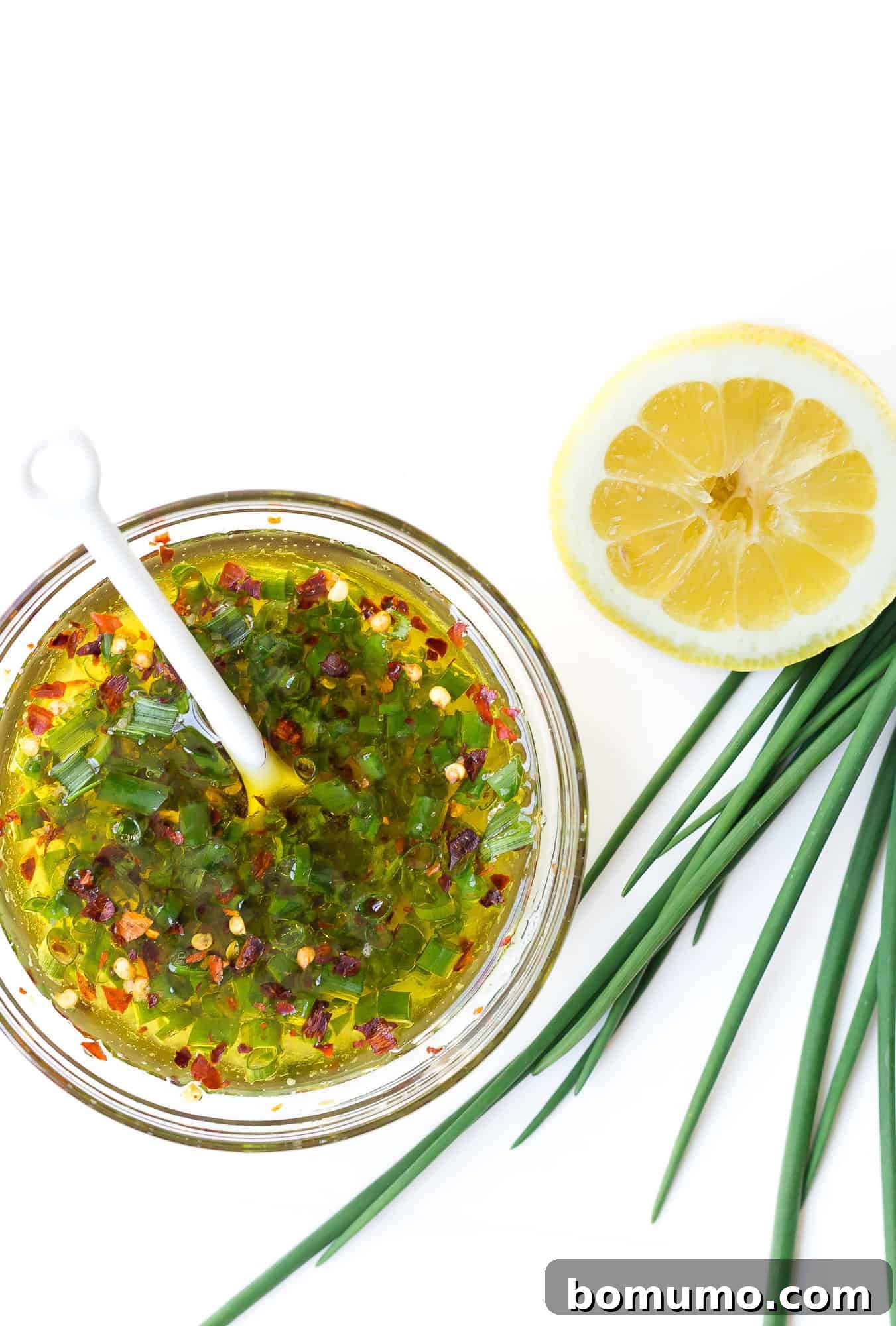 This flavorful baked salmon with lemon and chives is a taste of summer! It's the ultimate healthy, easy dinner idea, ready in 30 minutes. A small bowl containing the freshly prepared lemon, chive, olive oil, and red pepper flakes sauce.