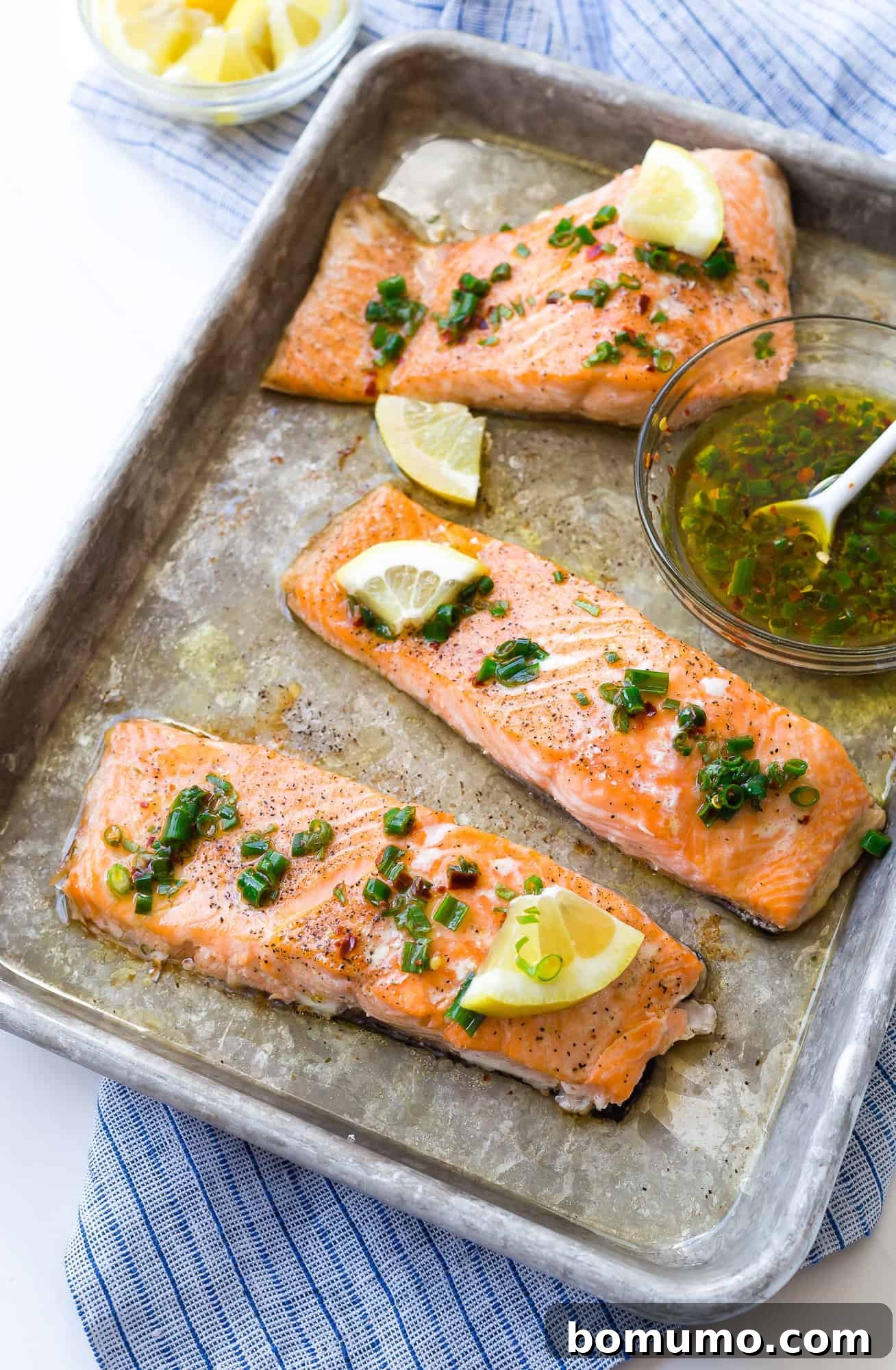 This flavorful baked salmon with lemon and chives is a taste of summer! It's the ultimate healthy, easy dinner idea, ready in 30 minutes. A stunning shot of sheet pan baked salmon, expertly topped with a vibrant lemon and chive sauce, alongside fresh lemon slices.