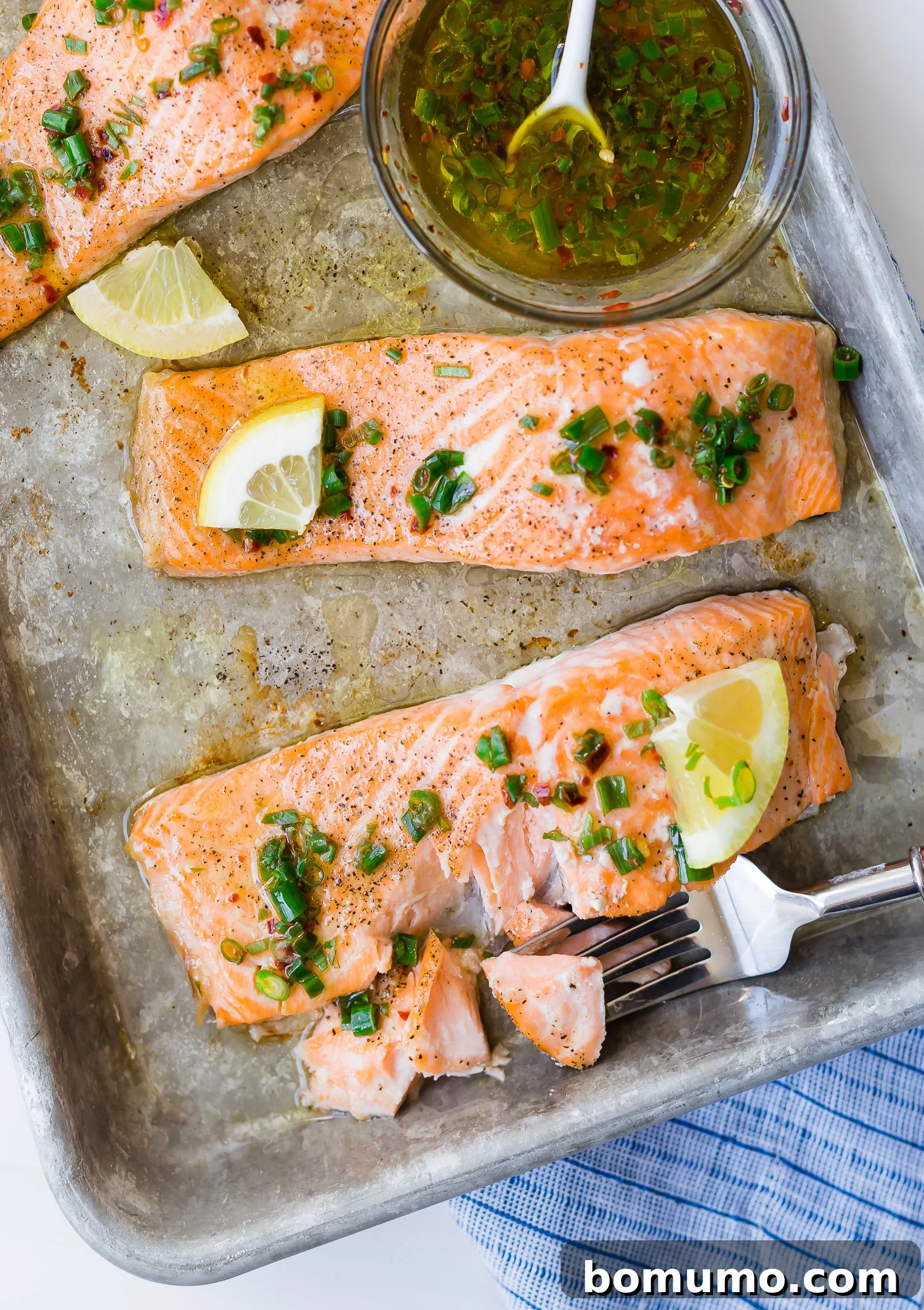 This flavorful baked salmon with lemon and chives is a taste of summer! It's the ultimate healthy, easy dinner idea, ready in 30 minutes. A fork gently flaking a piece of perfectly cooked salmon, showing its tender, moist texture.