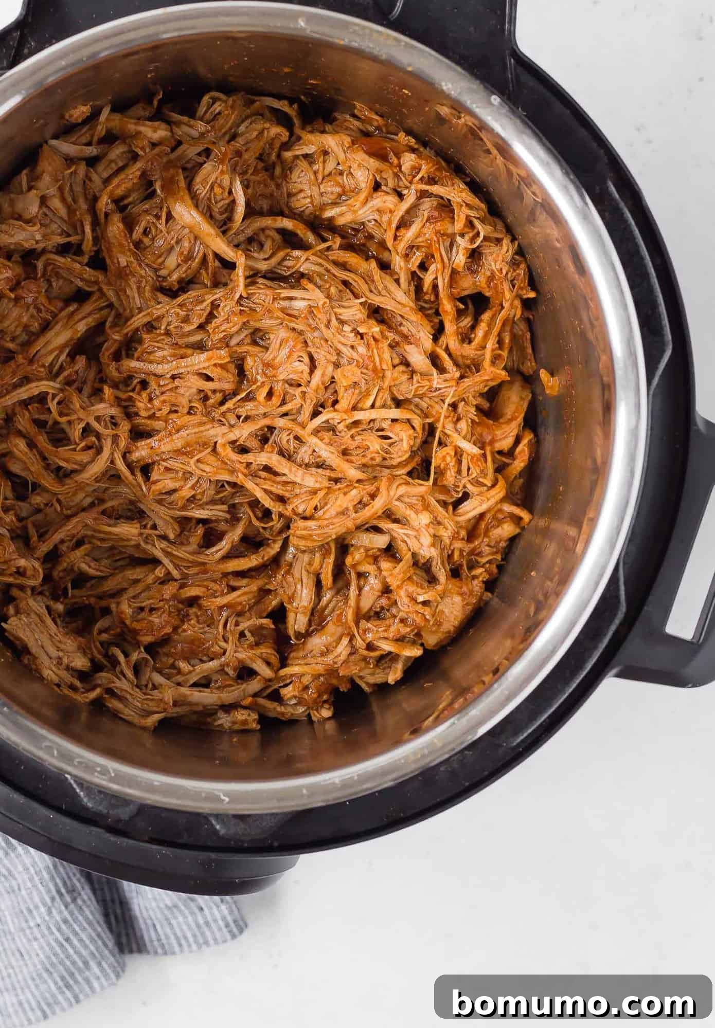 Overhead view of perfectly cooked Instant Pot Pulled Pork, ready for shredding, glistening with flavorful juices directly in the Instant Pot liner.