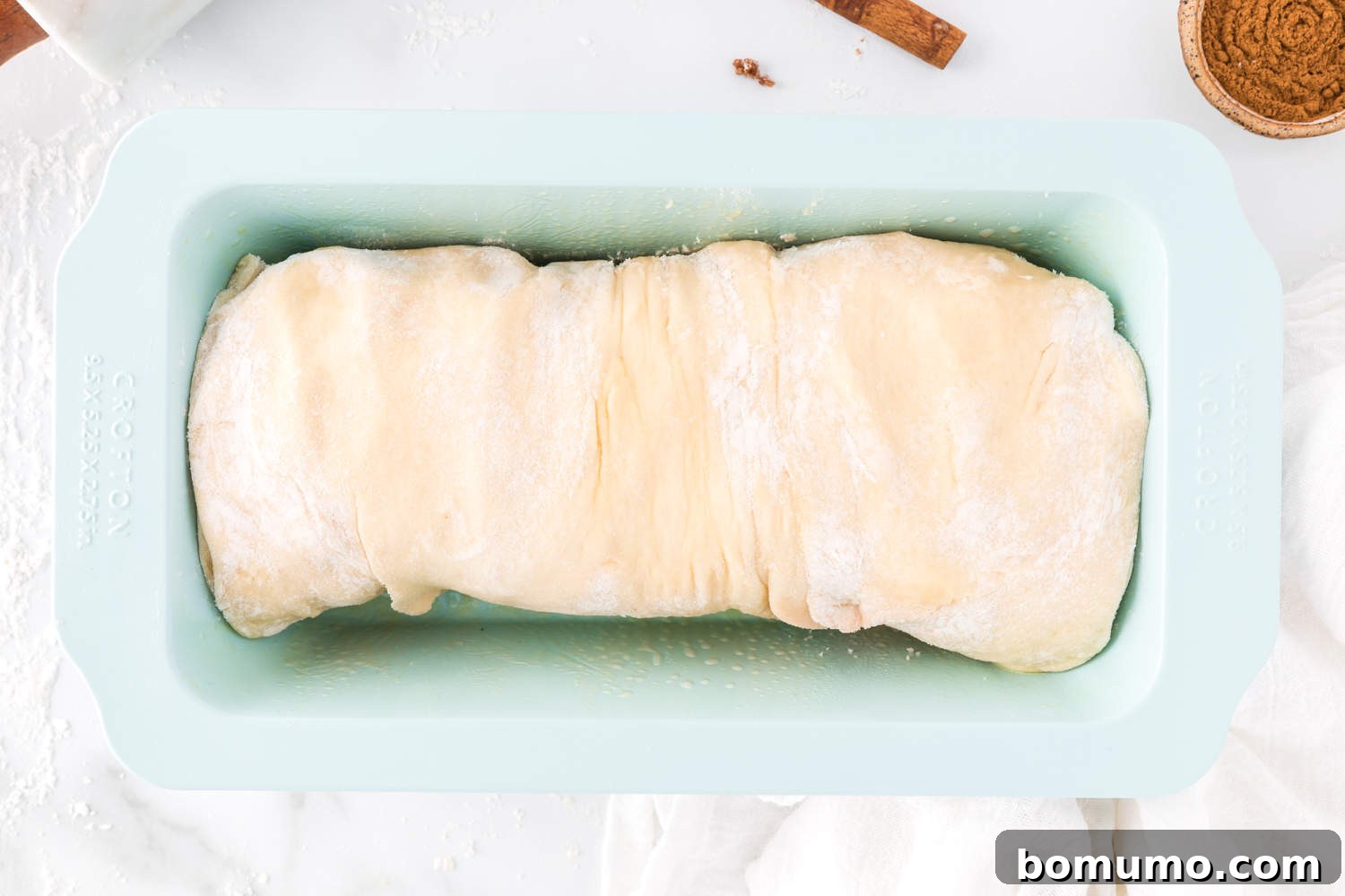 Shaped cinnamon swirl bread dough placed in a loaf pan, before its second rise.
