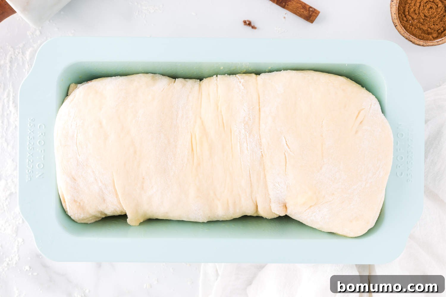 Cinnamon swirl bread dough beautifully risen in the loaf pan, ready for baking.