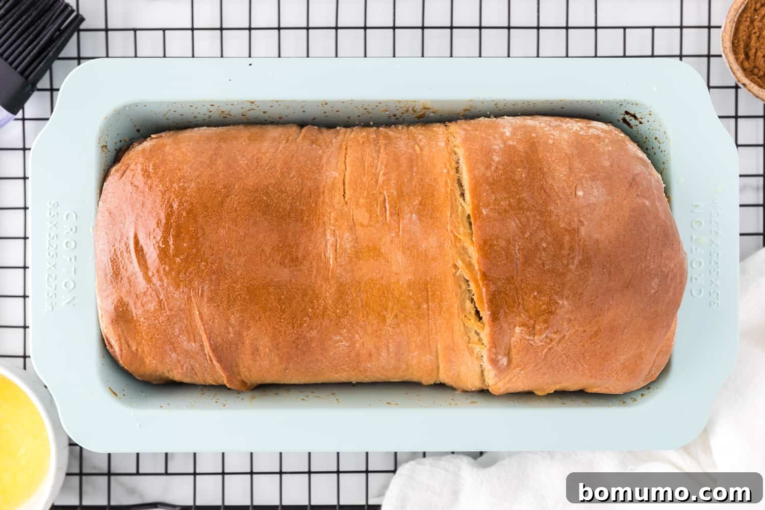 Freshly baked cinnamon swirl bread, golden brown and still in its loaf pan.