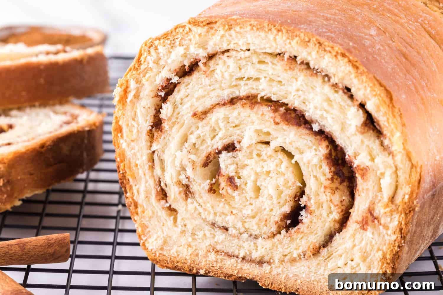 A slice cut from a warm loaf of homemade cinnamon swirl bread.