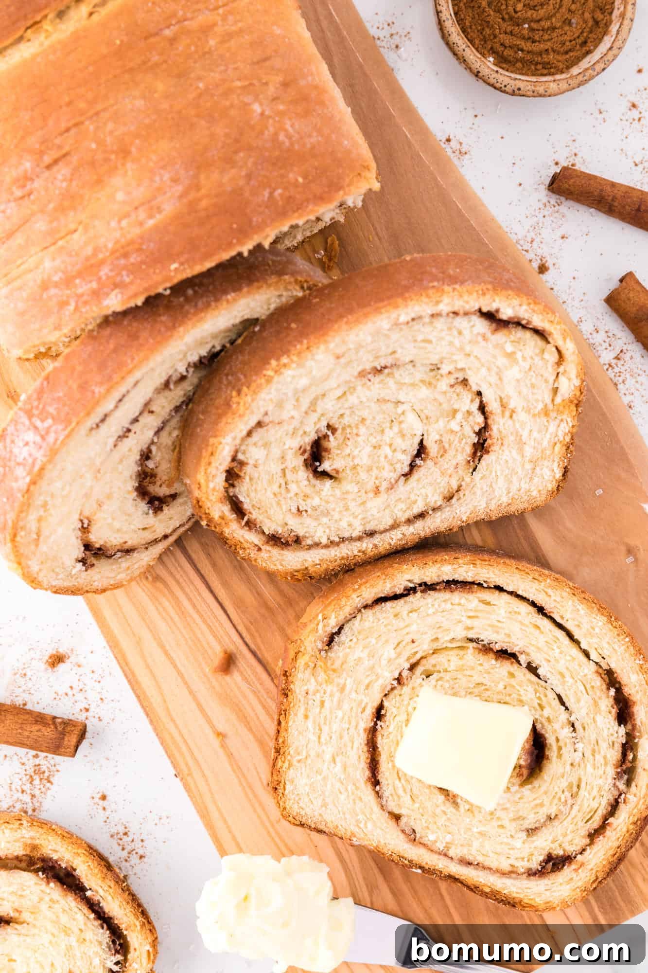 Close-up of a slice of cinnamon swirl bread topped with melting butter.