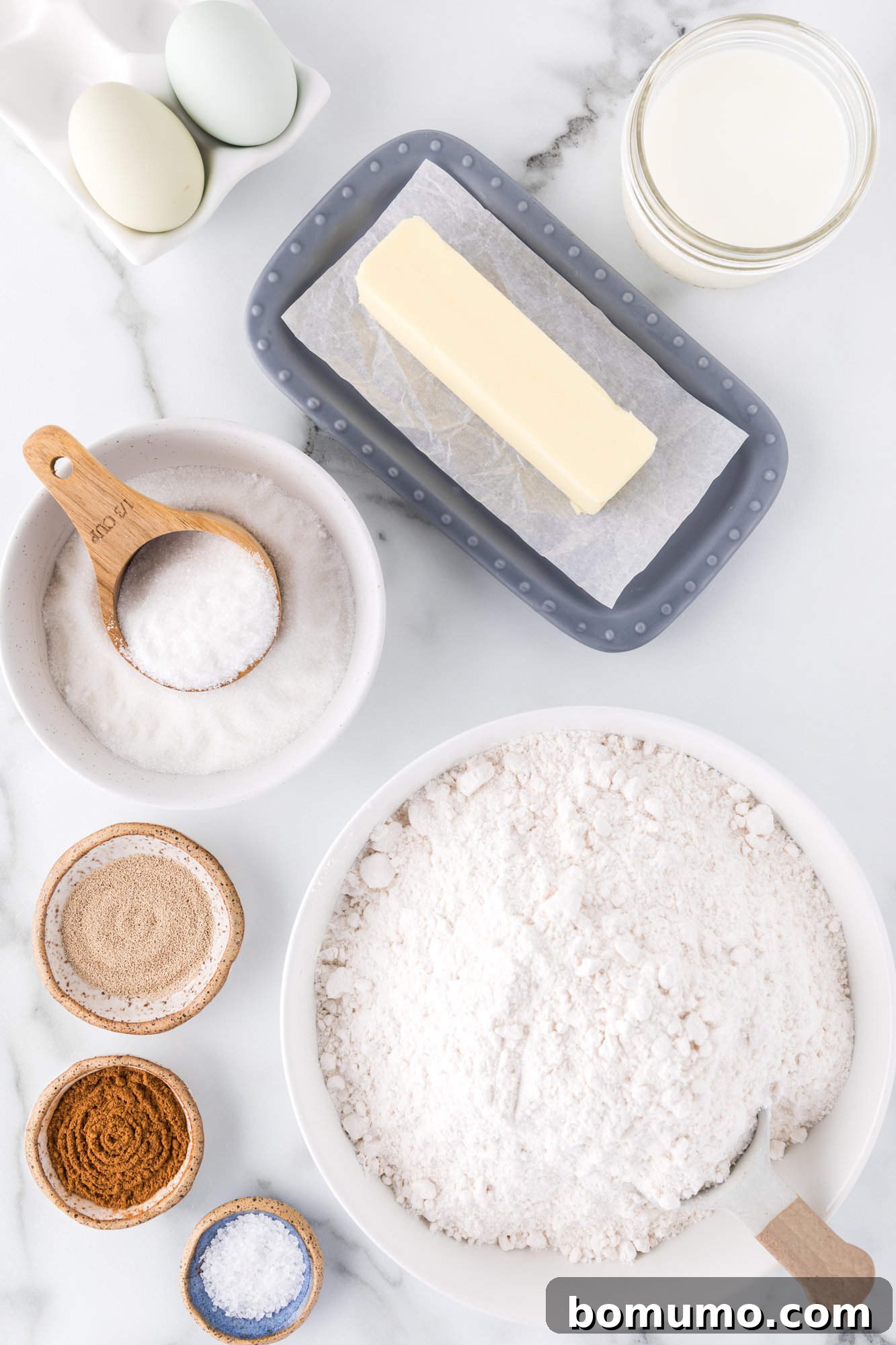 Overhead view of all the fresh ingredients laid out on a table, ready for baking homemade cinnamon swirl bread.