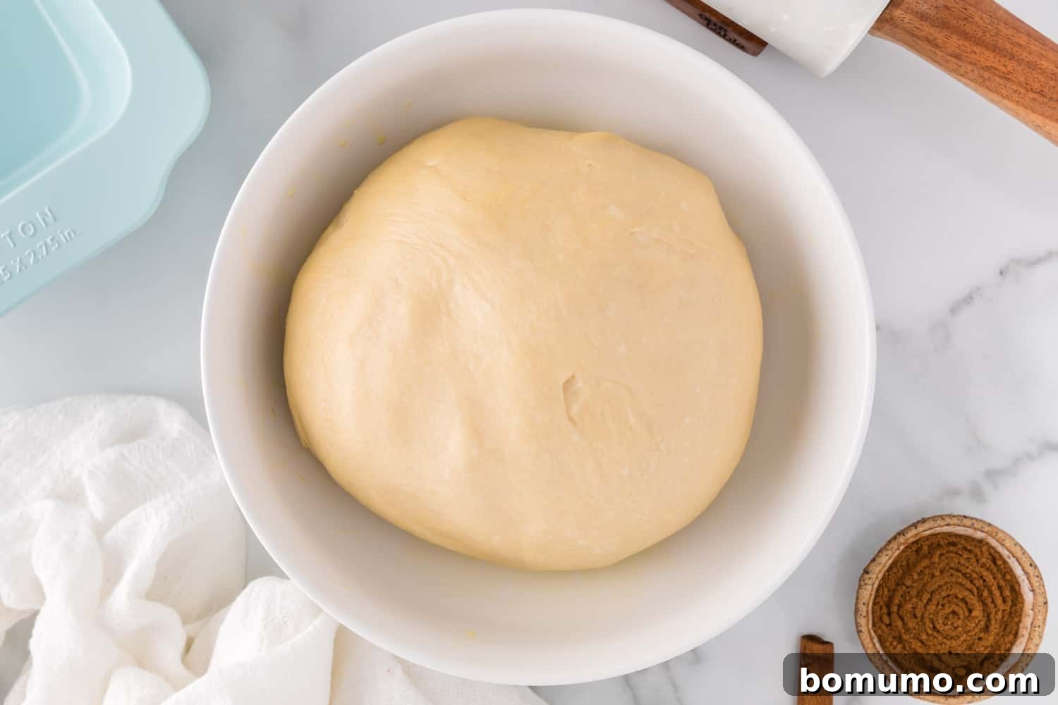 Smooth, elastic bread dough in a stand mixer bowl after sufficient kneading.