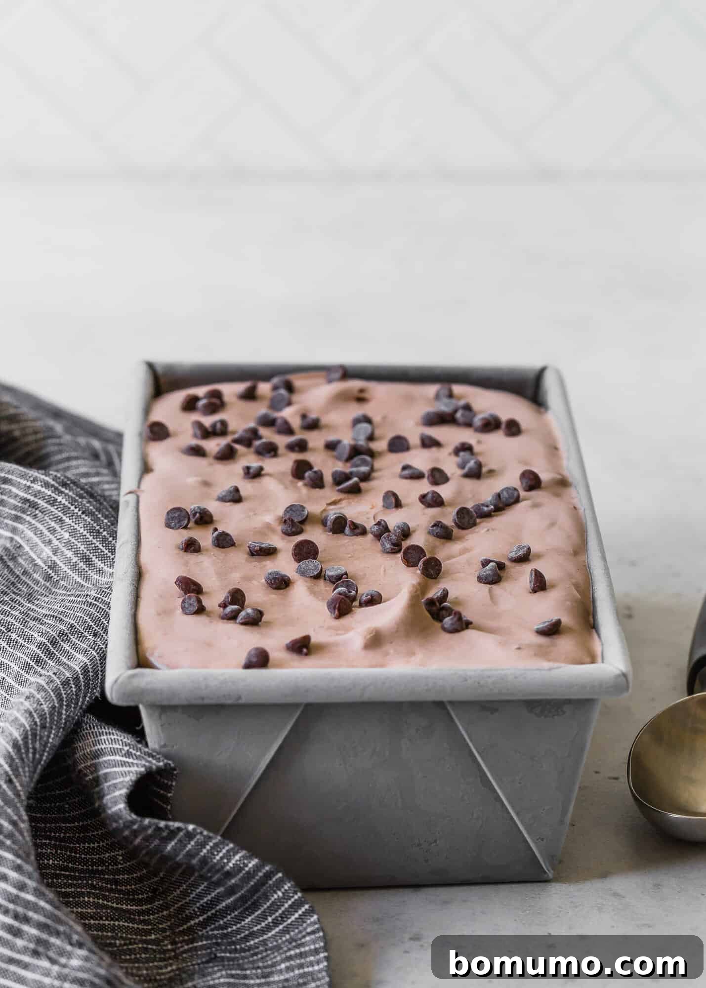 Smooth, rich chocolate ice cream setting in a metal loaf pan, ready for freezing.