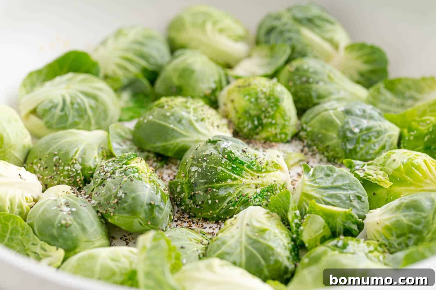 Brussels sprouts in pan, sprinkled with salt and pepper.