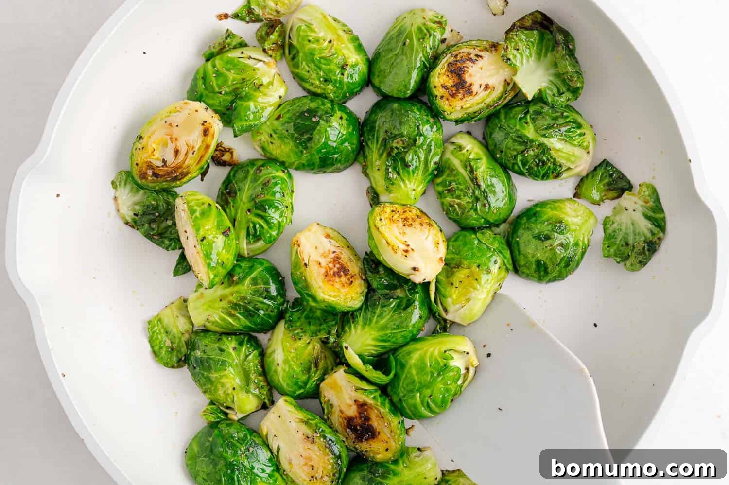 Brussels sprouts in a frying pan being stirred.