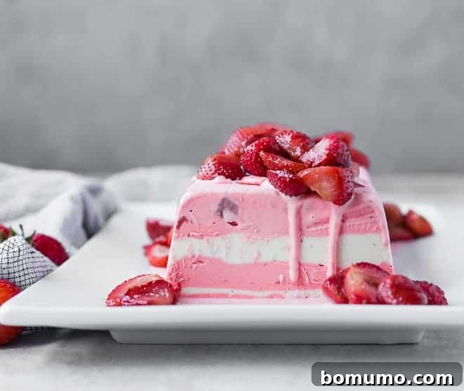 Front shot of a serving of ice cream terrine on white square plate, showcasing the beautiful layers and roasted strawberry topping.