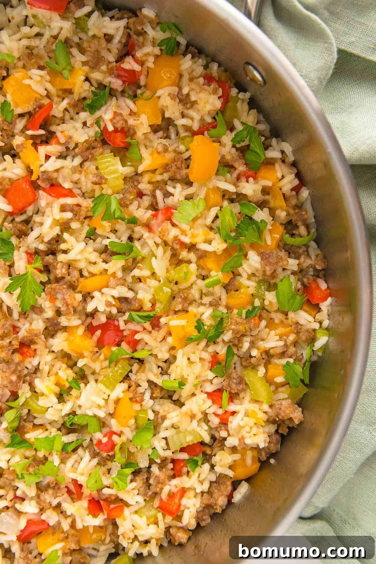 A vibrant display of cooked sausage, tender rice, and colorful bell peppers harmoniously combined in a large skillet, ready to be enjoyed.