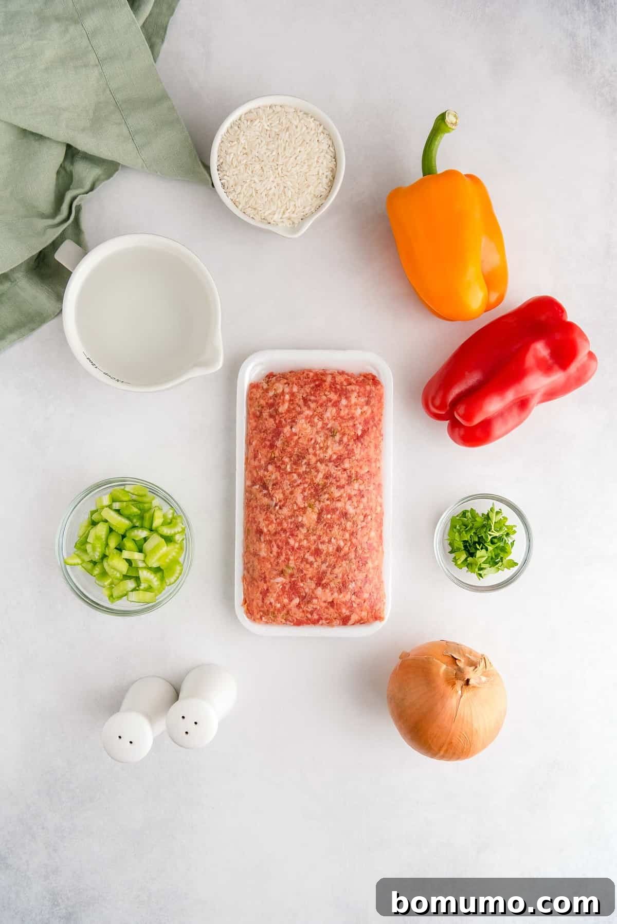 An overhead shot showcasing all the fresh, uncooked ingredients: bulk Italian sausage, colorful bell peppers, diced onion and celery, uncooked long-grain white rice, and a vibrant bunch of fresh parsley.