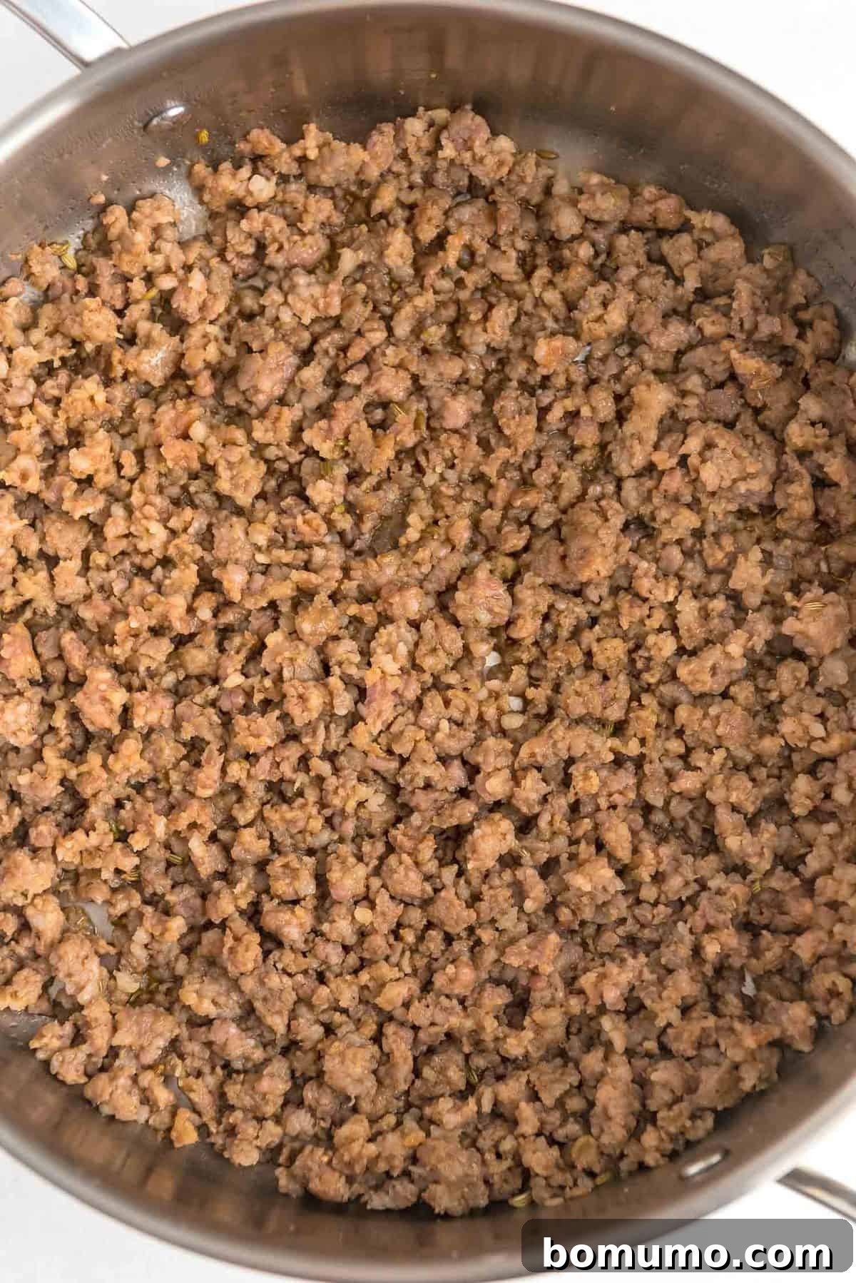 Perfectly browned and crumbled Italian sausage sizzling in a skillet, creating a delicious base for the one-pan meal.