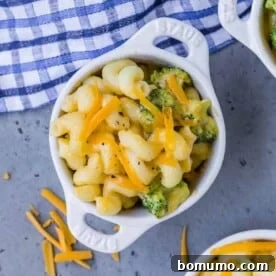 Overhead view of a small white bowl of instant pot mac and cheese with broccoli. Two other bowls are partially visible.