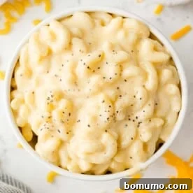 Overhead view of stovetop mac and cheese in a white bowl, sprinkled with pepper.