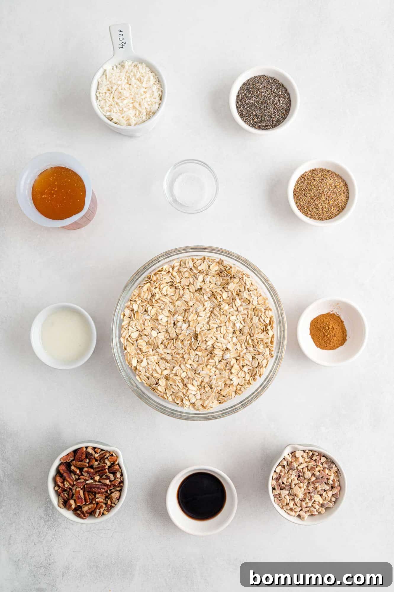 A curated display of raw ingredients for granola, prominently featuring a bowl of rolled oats, alongside nuts, coconut, and other dry components, ready for preparation.