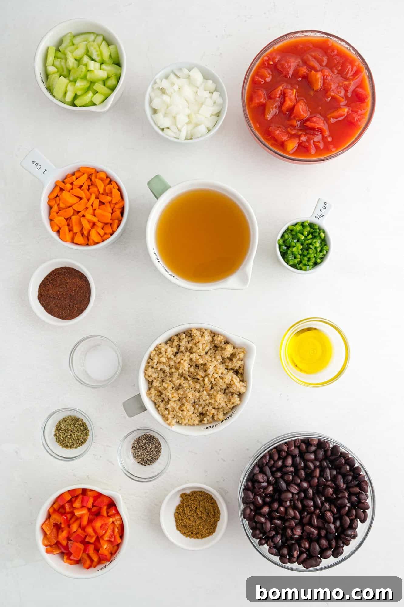 An overhead shot showcasing all the fresh ingredients for the vegetarian quinoa chili laid out in separate bowls, including vibrant vegetables, spices, black beans, and a bowl of cooked quinoa.